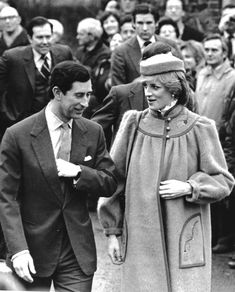 an old black and white photo of two people walking in front of a large crowd