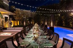 an outdoor dining area with tables and chairs next to a swimming pool at night time