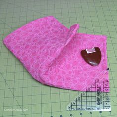 a piece of pink fabric with a heart shaped object on it next to a ruler