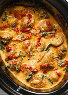 a crock pot filled with chicken, tomatoes and spinach