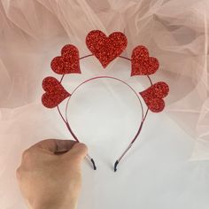 someone is making a heart shaped headband out of red glittery hearts on a white background