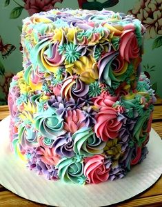 there is a multi colored cake with flowers on the top and bottom tiers that are made out of icing