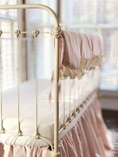 a white metal bed with pink sheets and ruffled bedspread on the bottom