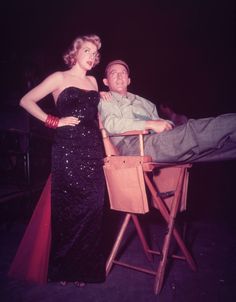 a man standing next to a woman on top of a wooden chair in front of him