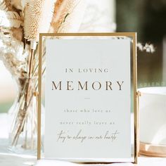 a memorial sign sitting on top of a table next to a vase filled with flowers