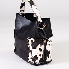 Who doesn't love cow print?! This baby is not only beautiful, but it's roomy too! Featuring two large exterior pockets, this bag has all the space you need for a day out. 11.5"h x 16"w, snap closure Black Bag With Cow Print For Everyday Use, Trendy Cow Print Bags For Everyday Use, Casual Everyday Bag With Cow Print, Rectangular Cow Print Travel Bag, Black Bucket Bag With Snap Closure For Travel, Casual Cow Print Bags For Daily Use, Brown Cow Print Bag For Everyday Use, Leather Cow Print Bag For Everyday Use, Brown Cow Print Bag