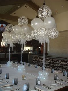 the table is set with silverware and white balloons