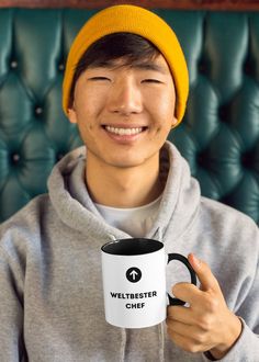 a man wearing a yellow hat holding a coffee mug