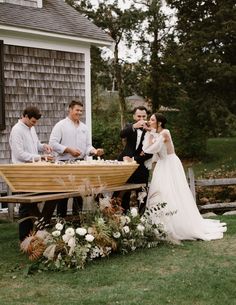 a bride and groom standing in front of a boat with their wedding party around it