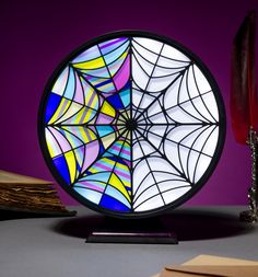 a stained glass plate with a spider web design on it next to a candle holder