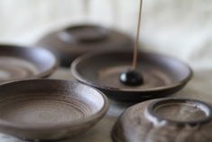 four black bowls sitting on top of a white cloth covered table next to each other