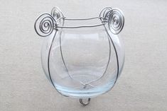 a glass vase sitting on top of a white table next to a metal holder with two handles