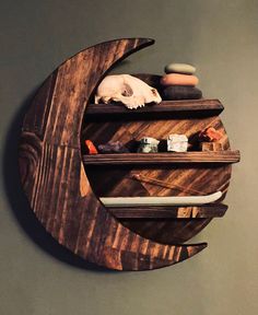 a wooden moon shelf with various items on it's sides and a skull in the middle