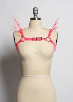 The neon version of the Replicant Chest Harness! Cyberpunk inspired harness made in colorful PVC. Dramatic spikes fan out at the shoulder to create a striking, avant garde, futuristic look. Fit is adjustable with buckle at chest. Silver-toned nickel plated steel hardware. Spikes are plastic zip ties/cable ties and are lightweight and flexible. Available in neon pink (shown) or lime green. Neon pink and neon orange PVC areUV reactive, the lime green PVC is NOT. All spikes colors are UV reactive. Adjustable Straps Harness For Party, Adjustable Strap Harness For Party, Punk Strapped Harness For Cosplay, Edgy Party Harness With Straps, Punk Style Party Harness With Adjustable Straps, Punk Style Harness With Adjustable Straps For Party, Edgy Strapped Party Harness, Edgy Strapped Harness For Parties, Edgy Adjustable Party Harness