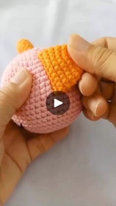 a person holding a pink and orange knitted toy