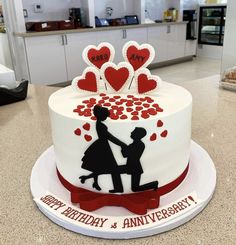 a white and red cake with hearts on it that says happy birthday and an anniversary