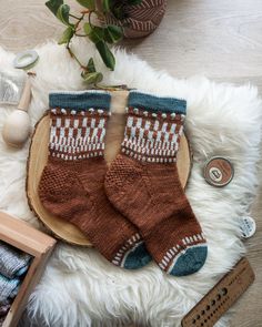 a pair of brown socks sitting on top of a white rug next to a plant