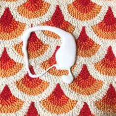 an orange and white crocheted blanket with a pair of headphones on it