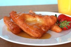 a white plate topped with pastries and strawberries next to a glass of orange juice