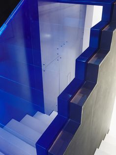 a blue and white stair case with glass panels on the bottom, in front of a black background