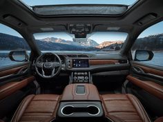 the interior of a vehicle with brown leather seats and mountains in the backgroud