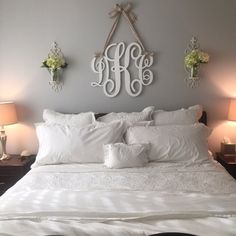 a bed with white sheets and pillows in a bedroom next to two lamps on either side of the headboard