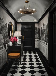 a black and white checkered floor in a hallway with a chandelier hanging from the ceiling