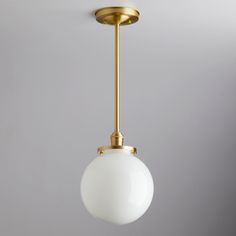 a white ball hanging from a gold colored ceiling fixture with a light bulb on it