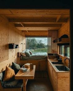 the interior of a tiny cabin with wood walls and flooring, including a kitchen area