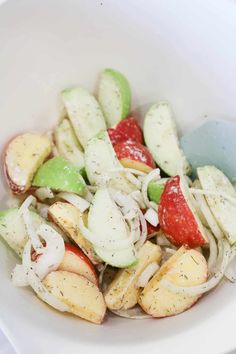 a white bowl filled with sliced up fruit and veggies on top of it