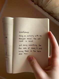 a hand holding an open book with writing on it that says mindfulness is doing an activity with no thought about the out come in mind