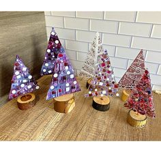 three small trees sitting on top of a wooden table next to a brick wall with white dots