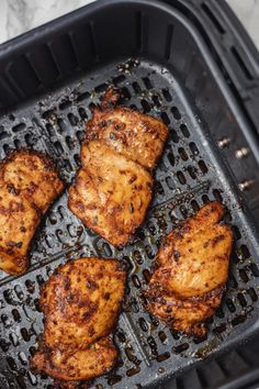 four pieces of chicken cooking in an air fryer