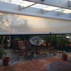 an outdoor patio area with chairs, umbrella and potted plants