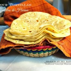 tortillas stacked on top of each other in a basket with an orange towel