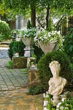 a garden filled with lots of white flowers and greenery next to a stone walkway