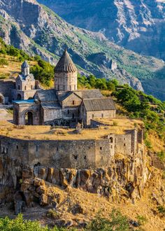 an old church perched on top of a cliff with mountains in the background and blue sky