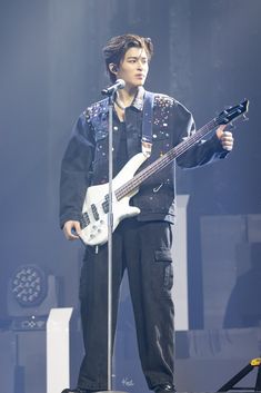 a man standing on top of a stage holding a guitar