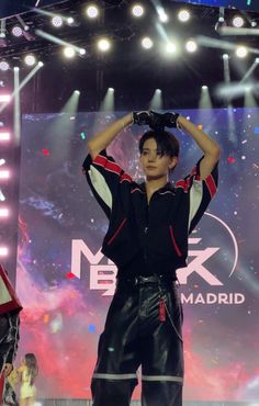 a man standing on top of a stage holding his hands to his head and wearing black pants