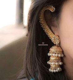 a close up of a woman's ear wearing gold jewelry