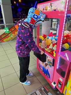 a young child is playing with a claw vending machine at the mall or shopping center