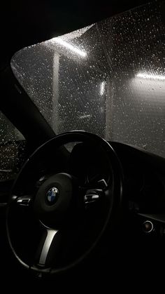 the inside of a car with raindrops on it's windshield and steering wheel