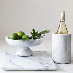 a marble bowl with limes and a bottle of wine