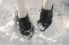 a person standing in the snow wearing black shoes and white socks with their feet up