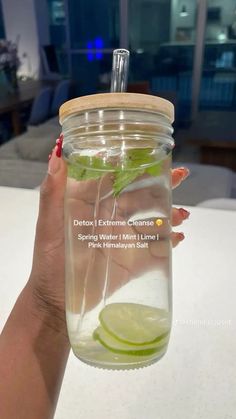 a person holding a mason jar filled with water and lime