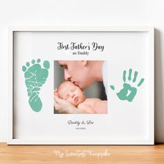 a baby's hand and foot prints are displayed in a white frame on a wooden table