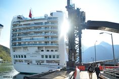 two people walking on a dock next to a large cruise ship