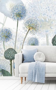 a white couch sitting next to a wall with blue flowers on it