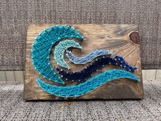 the string art is made to look like an ocean wave, with blue and white colors