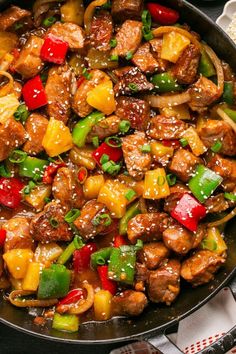 a skillet filled with meat and vegetables on top of a table next to utensils